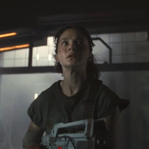 Cailee Spaeny looks terrified while holding a pulse rifle in an empty hallway in Alien: Romulus.