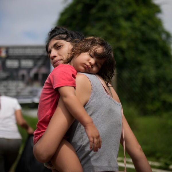 Venezuela migrant Naiber Zerpa holds her son Mathias Marquez as they arrive at a temporary camp after walking across the Darien Gap from Colombia, in Lajas Blancas, Panama, Friday, June 28, 2024. (AP Photo/Matias Delacroix)